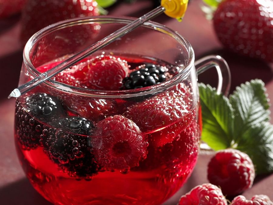 Fresh strawberries next to a glass of vibrant Berry Bliss mocktail