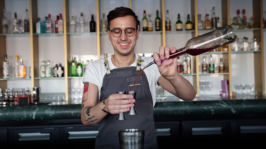 A bartender in a London bar presenting a beautifully crafted mocktail